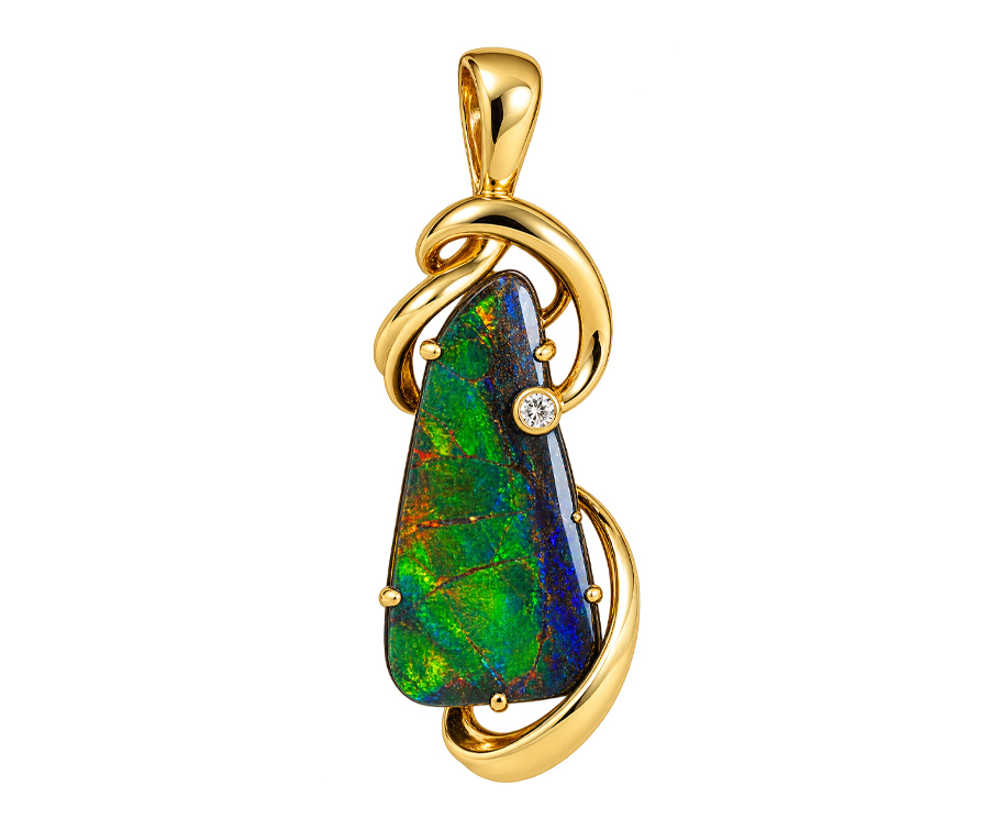 A striking combination of natural color and fine craftsmanship, this ammolite pendant features a vibrant gemstone with captivating iridescent flashes of green, blue, and red. Set in warm gold and accented with sparkling diamonds, the pendant brings together the unique beauty of an iridescent gemstone and the timeless elegance of precious metals. A distinctive statement piece, perfect for adding color and sophistication to both everyday wear and special occasions.